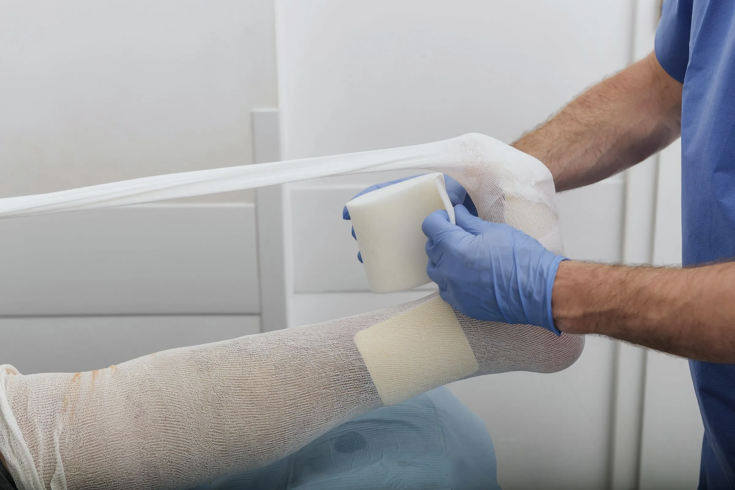 A clinician applying a compression dressing to a patient's lower leg